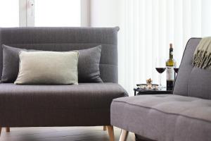 a living room with a couch and a glass of wine at Modernes Ferienhäuschen am Zeulenrodaer Meer mit Terrasse, Klimaanlage, 1 SZ, max 3 Gäste in Zeulenroda