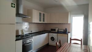 a kitchen with a stove and a sink and a table at big apartment in the beach in Zambujeira do Mar