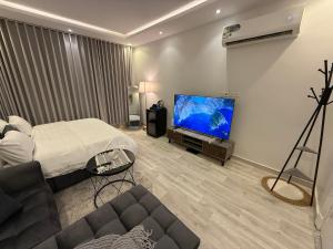 a living room with a bed and a flat screen tv at شقة تأجير يومي استوديو جديد بأثاث هادئ وأنيق in Riyadh