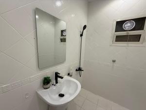 a white bathroom with a sink and a mirror at شقة تأجير يومي استوديو جديد بأثاث هادئ وأنيق in Riyadh