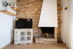 a living room with a stone fireplace with a television at AIGUAMARINA - Amor al mar y la vida in L'Ampolla