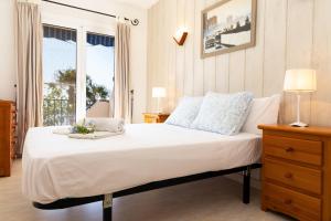 a bedroom with a large white bed with a window at AIGUAMARINA - Amor al mar y la vida in L'Ampolla