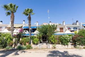 a large white building with palm trees and plants at AIGUAMARINA - Amor al mar y la vida in L'Ampolla