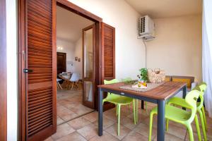 サン・テオドーロにあるMaison Apartments San Teodoro Centerの木製のテーブルと緑の椅子のあるダイニングルーム +5枚の写真
