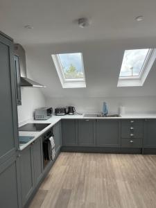 a kitchen with gray cabinets and two windows at The Silverdale Court No6 in Farnborough