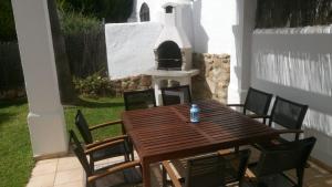 a wooden table and chairs on a patio with a grill at Adosado tres habitaciones, en Bahía de la Plata, Zahara de los atunes in Zahara de los Atunes