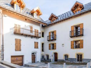 una casa blanca con ventanas y balcones de madera en Appartement rénové au coeur de Mônetier-les-Bains avec services inclus - FR-1-808-14, en Le Monêtier-les-Bains