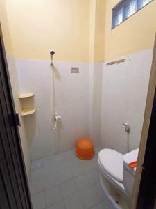 a bathroom with a shower and a toilet with an orange seat at HOMESTAY RJS Pulau Tidung NWR in Pulau Tidung-besar