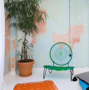 a green chair in a room with a plant at Trilogy Experimental in Thessaloniki