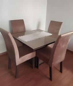 a glass dining table with two chairs and a table with a piece of paper at Apartamento Central com suite Panazzolo 7 minutos do centro in Caxias do Sul