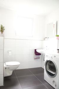 baño blanco con lavadora y lavamanos en Ferienhaus Marina, en Baden-Baden