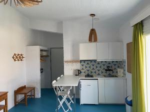 a kitchen with white cabinets and a table and chairs at Manolis' House in Skiathos
