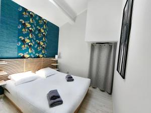 a bedroom with a white bed with a painting on the wall at Location vacances T3 à Cannes in Cannes