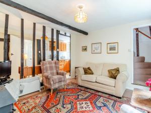 un salon avec un canapé et une télévision dans l'établissement Oaklawn Cottage, à Eye