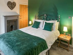 a bedroom with a large bed with green walls at Willow Cottage in Beverley