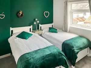 two beds in a room with green walls at Willow Cottage in Beverley