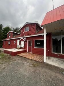 a red house with a wooden deck in front of it at Thessalon Luxury House -Space Share in Thessalon