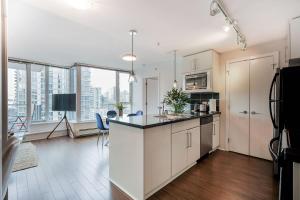 Una cocina de apartamento con gabinetes blancos y una ventana grande. en Gorgeous Unit with City Views, en Vancouver