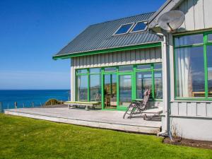 a house with a deck with a bench and the ocean at Longa House in Big Sand