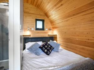 a bed in a room with a wooden wall at Luna Holiday Pod - Uk48590 in Church Stretton