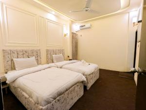 zwei Betten in einem Hotelzimmer mit weißen Laken in der Unterkunft White Rose BnB Family - Near Millennium Mall - Airport - National Stadium in Karatschi