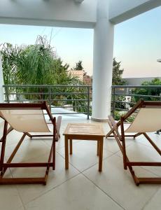two chairs and a coffee table on a balcony at Iloma Villa 6 km from Nafplio in Dhalamanára +45 photos