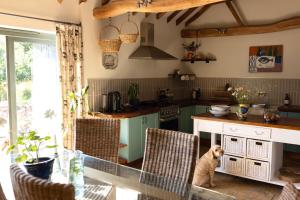 a kitchen with a table and a dog sitting on the chairs at Husk in Thorington