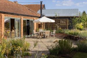 a patio with a table and chairs and an umbrella at Husk in Thorington