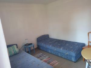 a bedroom with two beds and a table and a chair at Bacshegyi Vendeghaz 2 in Káptalantóti