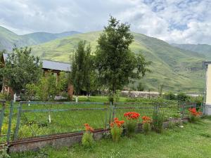 a fence with flowers in a yard with mountains at Casa KamArea in Kazbegi