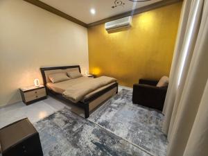 a small bedroom with a bed and a chair at NatureLand Beach Villa in Al Mughayrāʼ