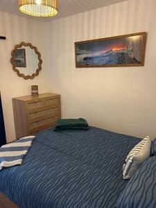 une chambre avec un lit, une commode et un miroir dans l'établissement The Cosy Cabin, à Pembrokeshire