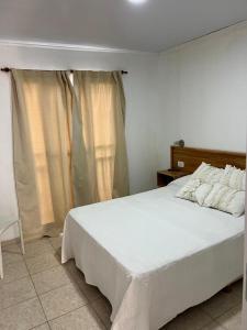 a bedroom with a white bed and a window at Bungalows Plaza Termal in Federación