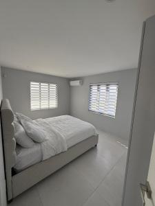 ein weißes Schlafzimmer mit einem Bett und zwei Fenstern in der Unterkunft Modern Home In Noord in Noord