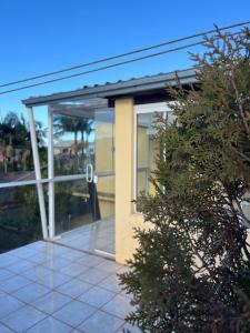 un edificio con una porta a vetri e un albero di Apartamento amplo 300m da praia a São Lourenço do Sul