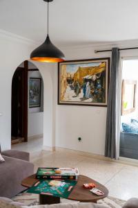 a living room with a table and a painting on the wall at Seabreeze 2BR Haven Ocean Walk and Sunsets in Tamellalt