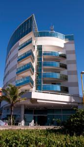 a building with a palm tree in front of it at Comfort Suites Macaé in Macaé