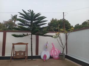 Una habitación con una palmera y algunos conejos rosas. en Kostel 77 Jepara, en Jepara