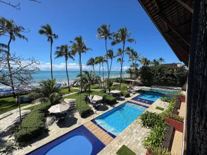 a view of a pool with palm trees and the ocean at Baobá Residence Porto de Galinhas Beira Mar na Vila in Porto De Galinhas