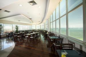 a dining room with tables and chairs and windows at Royal Kingdom Macaé in Macaé