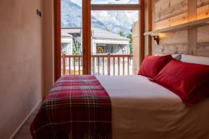 een slaapkamer met een bed met rode kussens en een raam bij Méijon Salluard RTA in Courmayeur