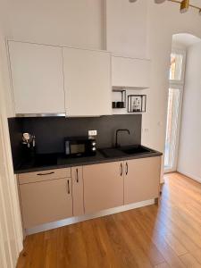 a kitchen with white cabinets and a black counter top at La Perla Centre in Zagreb