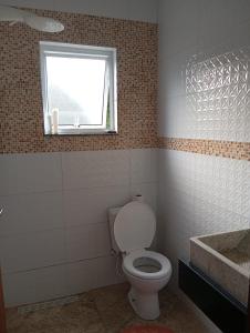 a bathroom with a toilet and a window and a sink at Marta's house in Peruíbe