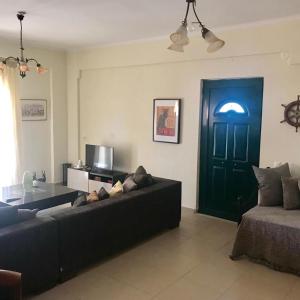 un soggiorno con divano nero e porta blu di Capt Tassos Summer House in Dassia a Città di Corfù