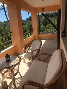 balcone con sedie, tavolo e finestre di Capt Tassos Summer House in Dassia a Città di Corfù