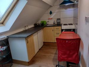a small kitchen with a red stool in a attic at Comfy Studio - Sleeps 2 Near Warwick University in Coventry