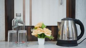 a tea kettle and a vase with flowers on a counter at Raahi - 3 Bedroom Flat Near Kashi Vishwanath in Varanasi
