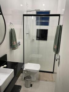 a bathroom with a toilet and a glass shower at Apartamento novo com garagem e ar condicionado in São Lourenço