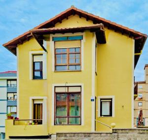 a yellow house with a brown roof at Villa Olas y Llamas in Santander