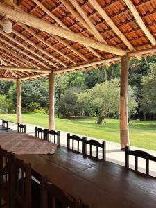 ein großer Holztisch mit Stühlen unter einem Pavillon in der Unterkunft Sítio Cantinho da Roça Perobas in Paraju